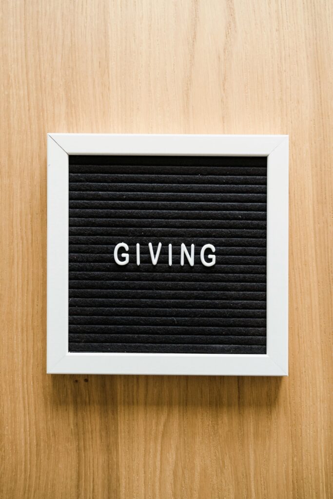 Black letter board with the word 'GIVING' framed in white on a wooden background.